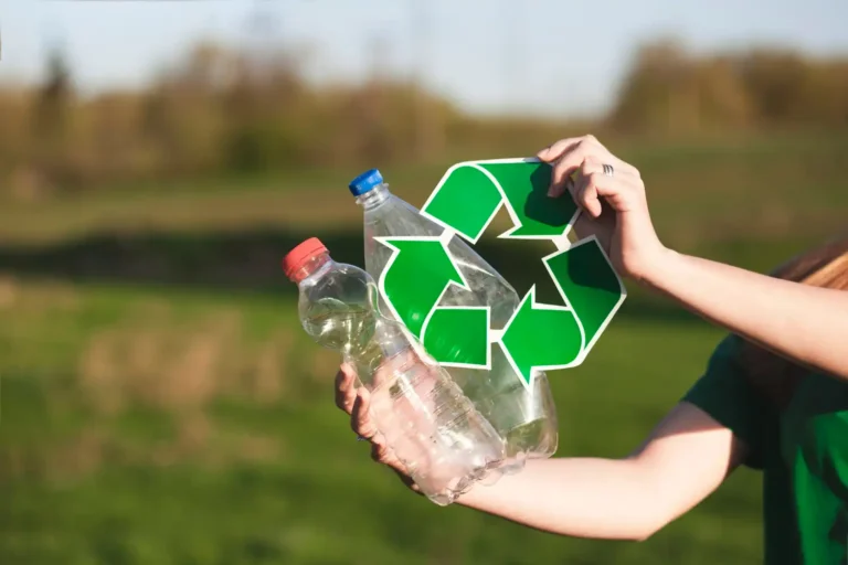 Hands holding plastic bottles with recycling symbol